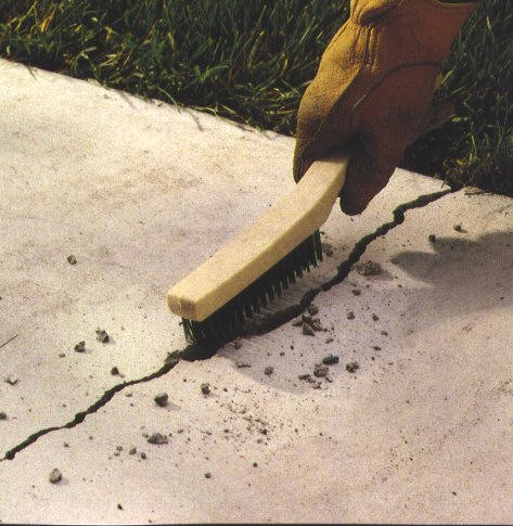 wire brush to clean crack in concrete slab for repair